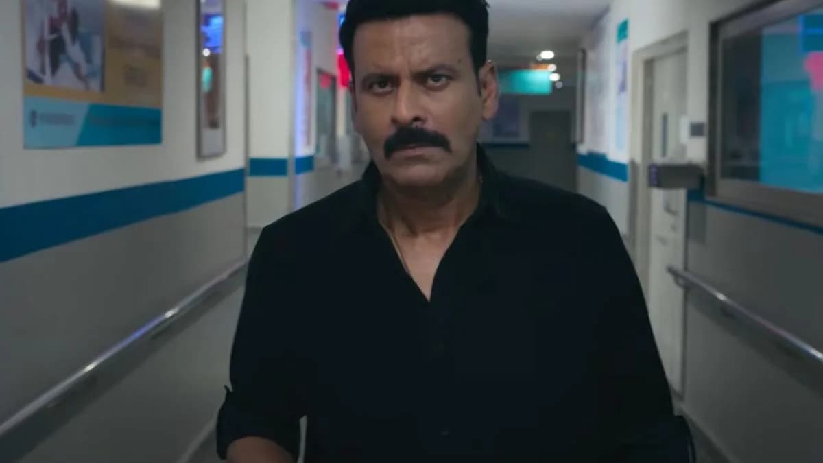 Manoj Bajpayee in a tense expression, standing in dim light, holding a file. Behind him, blurred city lights flicker.
