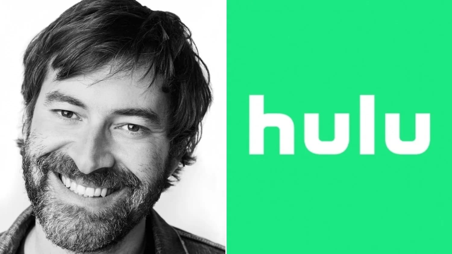 Mark Duplass in a suit, standing in front of a glass building in San Francisco, looking serious.