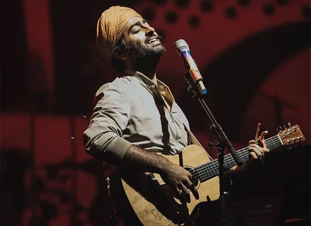 Arijit Singh performing on a large stage with LED screens and pyrotechnics.