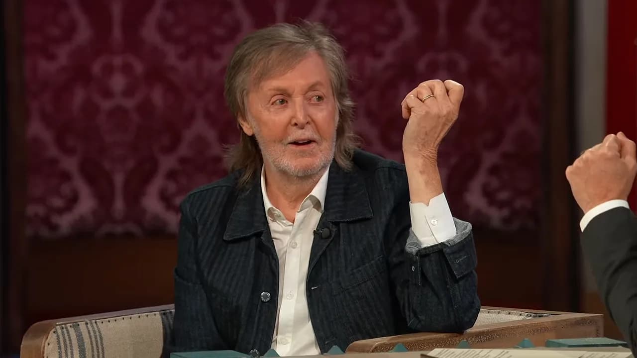 Paul McCartney on Jimmy Kimmel Live! holding a guitar, smiling.