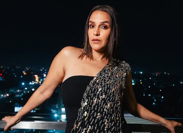 Neha Dhupia speaking on stage at an entertainment industry panel alongside JioStar executive Alok Jain