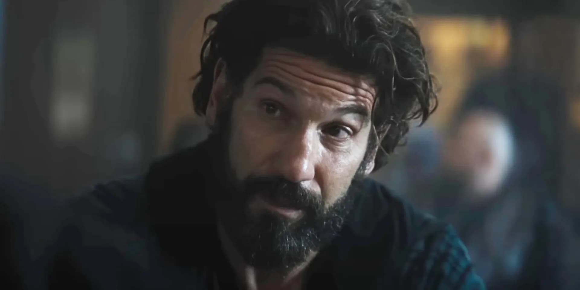 A dimly lit office. A man in a hoodie stares at a screen. His face is tense. The words 'THE AMATEUR' glow faintly in the corner.