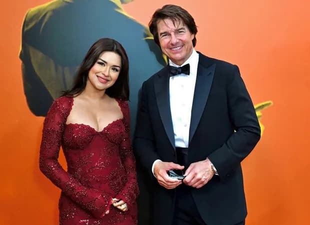 Avneet Kaur in a wine‑red embellished gown standing beside Tom Cruise at the Digger London premiere