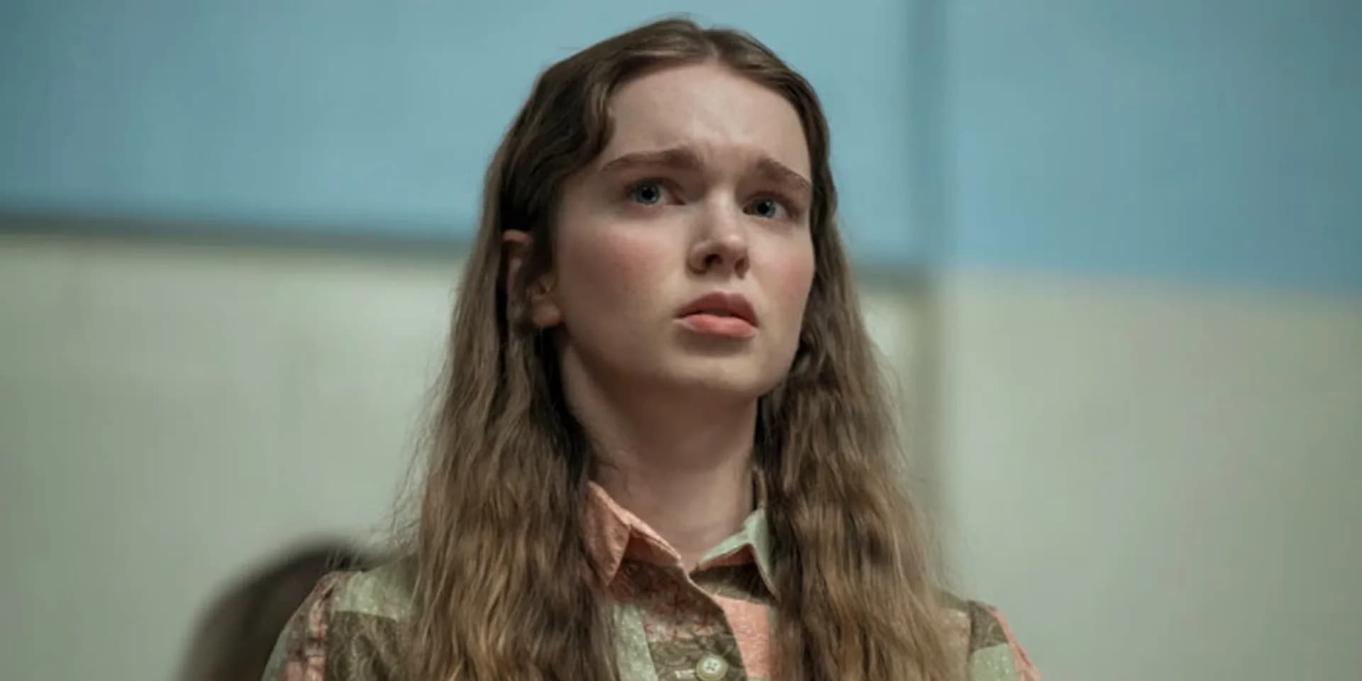 A dark, moody image of a teenage girl in a school hallway, eyes wide, shadows stretching behind her. A faint red glow pulses from beneath her feet.