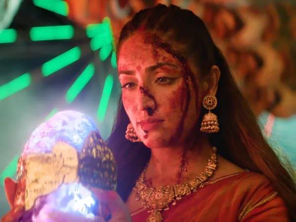 Yami Gautam in a dark daayan costume from the Nayyi Navelli trailer, standing in a traditional Indian doorway.