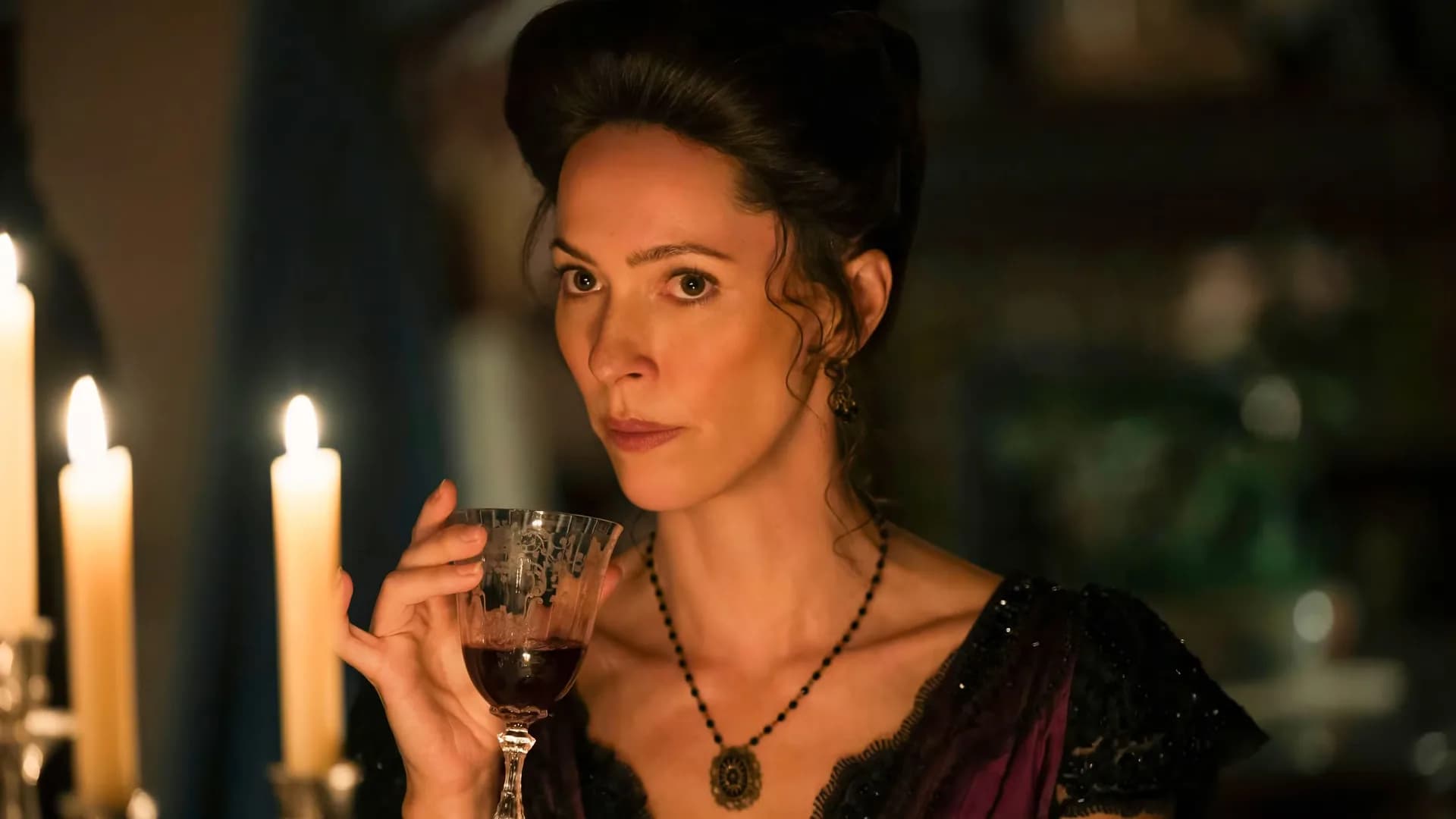 Rebecca Hall in costume as Abby Borden, wearing a period dress and a sly expression, on the set of Monster: The Lizzie Borden Story