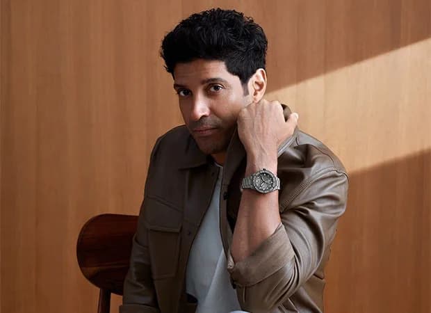 Farhan Akhtar in a tailored suit, holding a sleek Emporio Armani watch