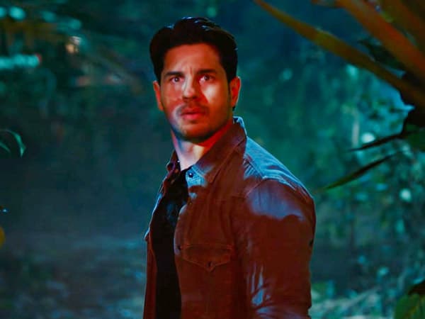 Sidharth Malhotra and Tamannaah Bhatia in a forest setting from The Vvaan trailer, with a village in the background.