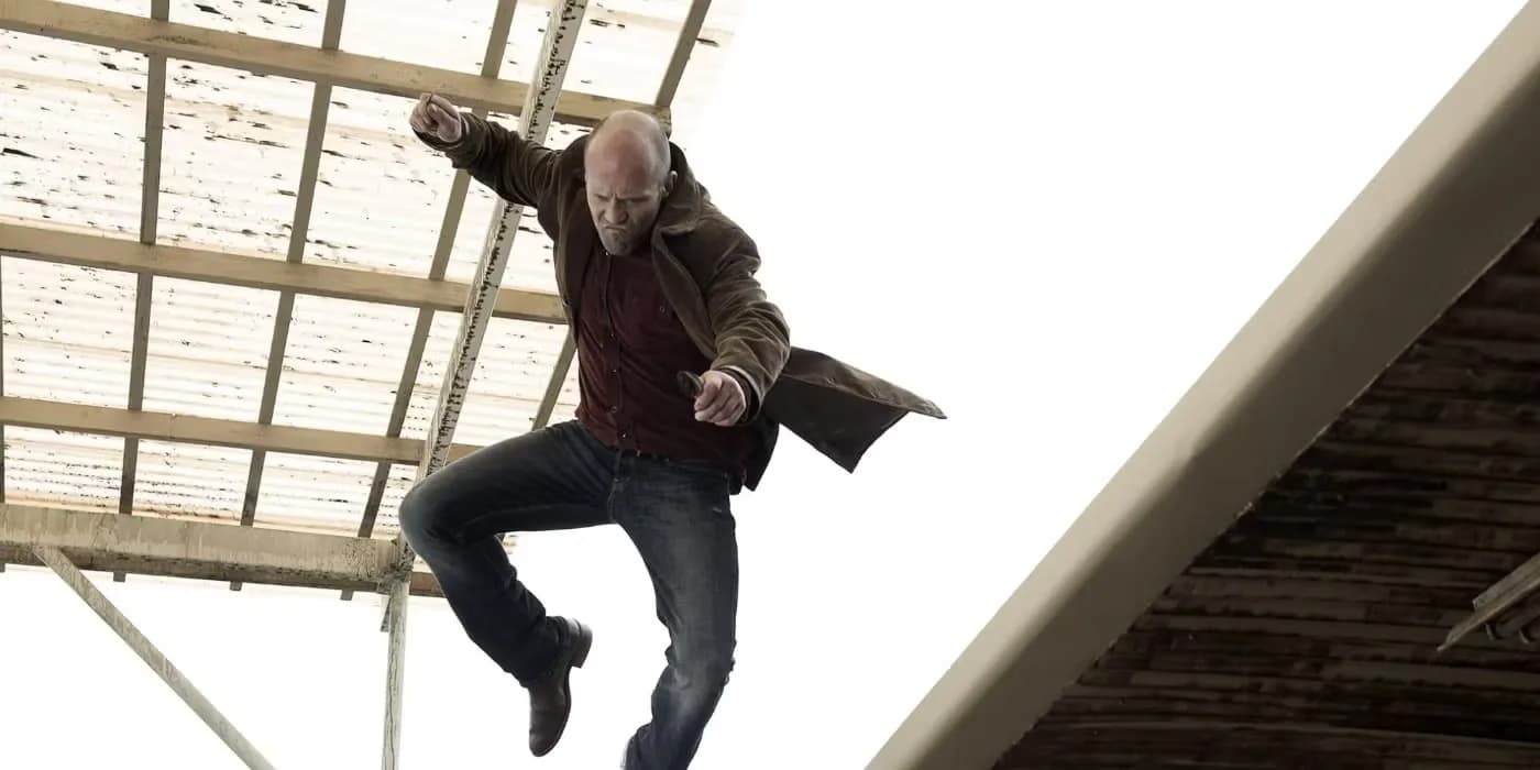 Jason Statham in a grey hoodie, standing in front of a neon-lit Las Vegas alley, eyes locked ahead.