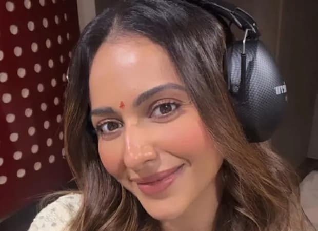 Rakul Preet Singh wearing dubbing headphones inside a sound studio, smiling at the camera