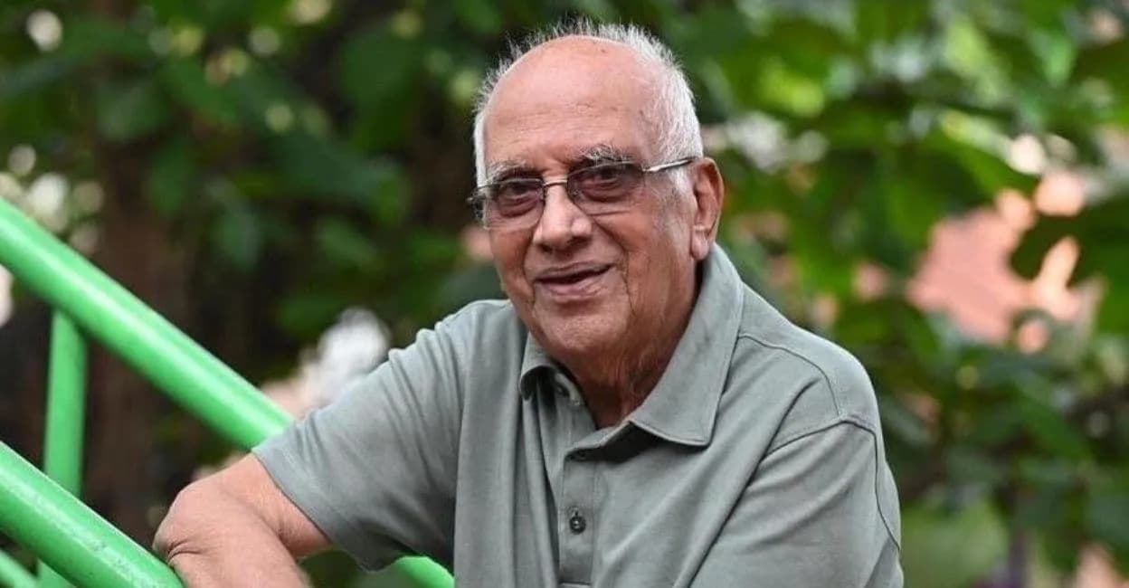 Portrait of filmmaker Singeetham Srinivasa Rao in his later years, seated, wearing glasses and a traditional shirt.