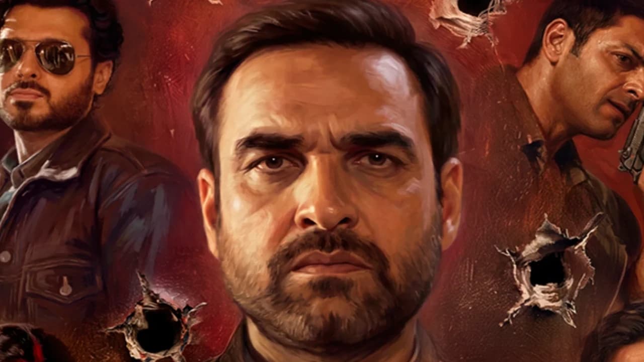 Pankaj Tripathi and Ravi Kishan standing amid a smoky set of Mirzapur: The Movie, with the film's title logo overhead.